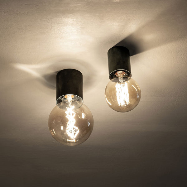 Two warm-toned globe light bulbs with exposed filaments, casting light on a ceiling.