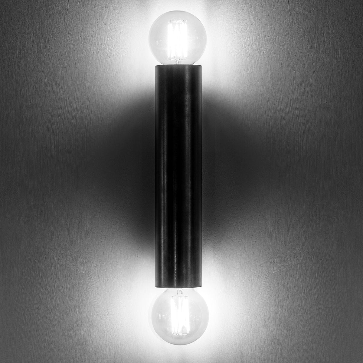 The contemporary black wall light illuminates a wall, creating an elegant ambiance.