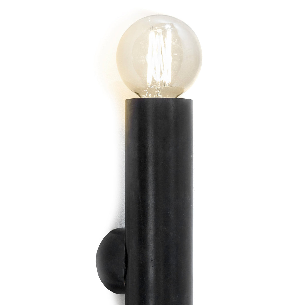 A close-up of the black wall light, highlighting the industrial design with an exposed bulb.