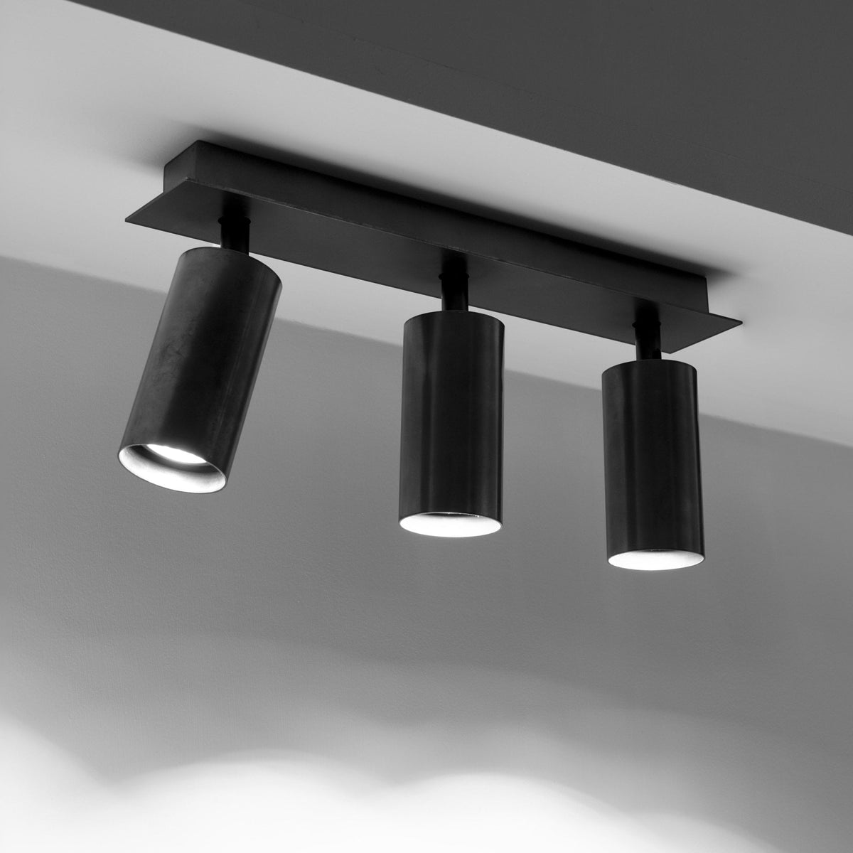 A sleek black three-spotlight ceiling fixture illuminates a modern room with adjustable lighting.