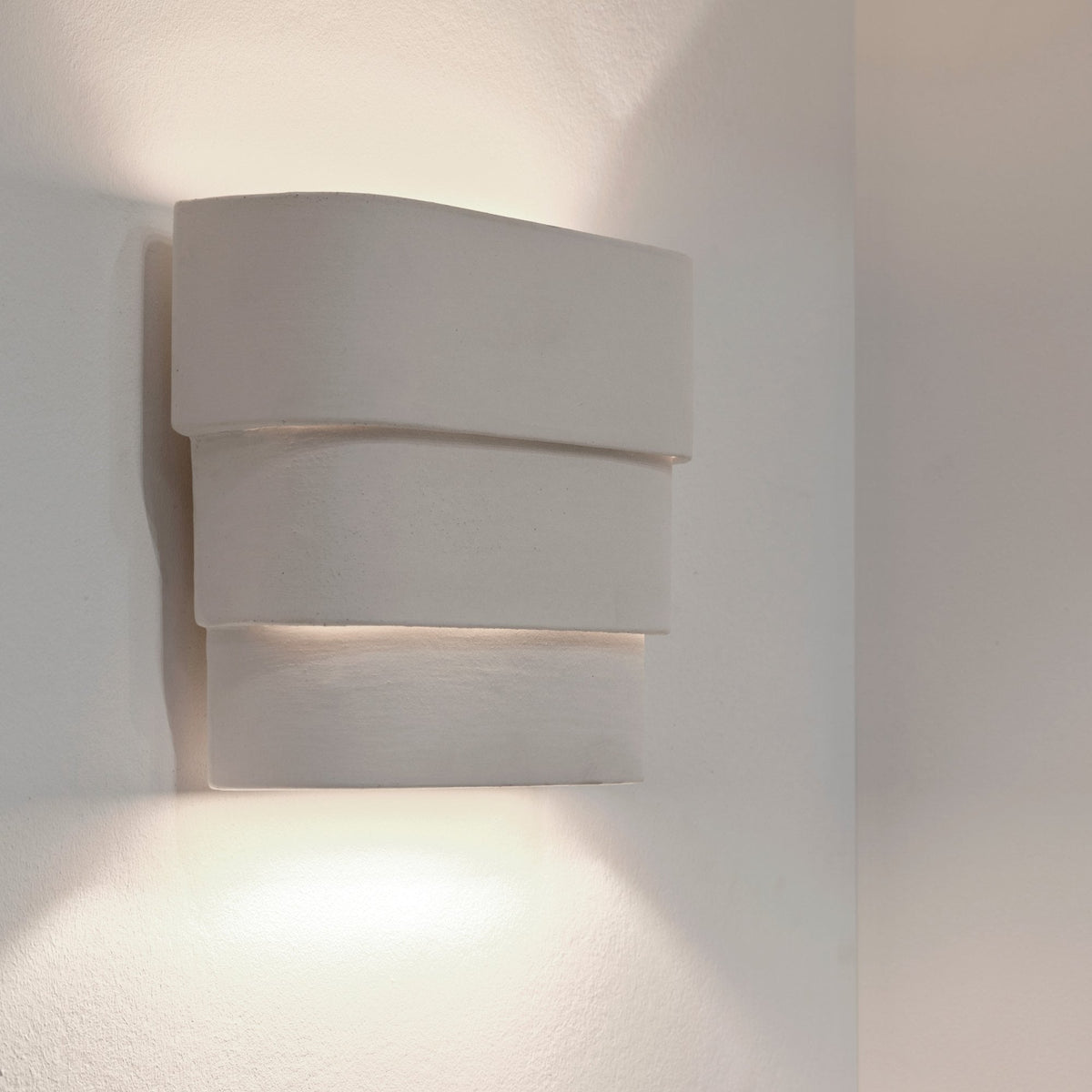 A modern, three-tiered rectangular wall light providing subtle, ambient up and down lighting.
