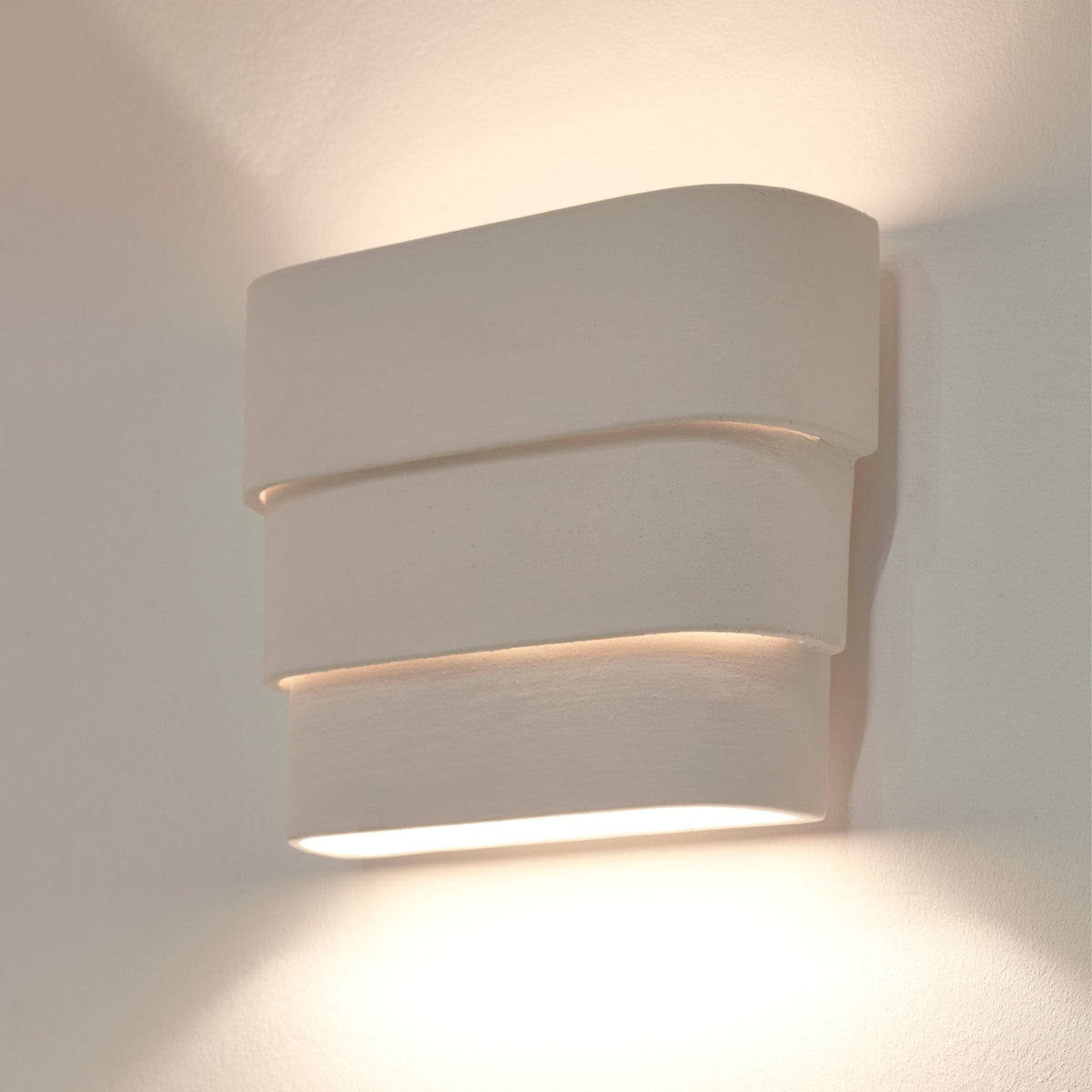 A modern, rectangular wall light with three horizontal layers, casting light upwards and downwards.