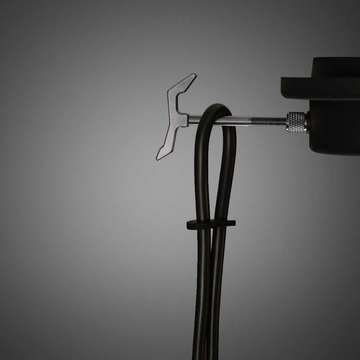 A close-up of a black cable neatly secured with a tie, attached to a metal hook and a threaded screw mechanism.