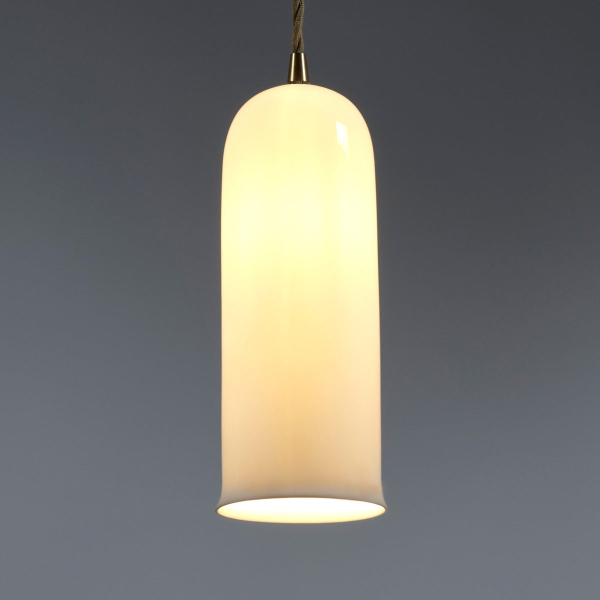 A white glass pendant light illuminated against a grey background.