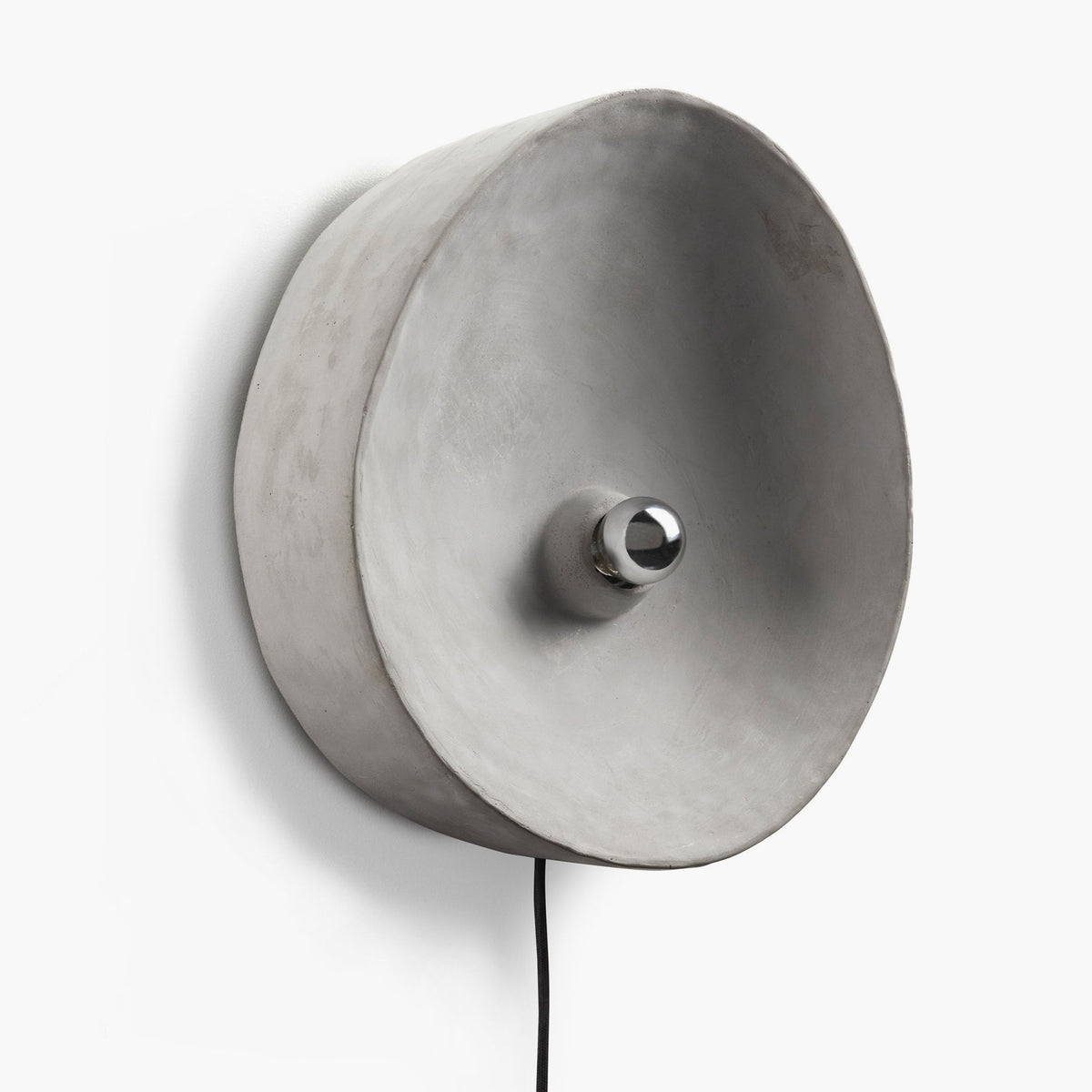 A circular grey wall light with a chrome-capped bulb facing outwards, on a white wall.