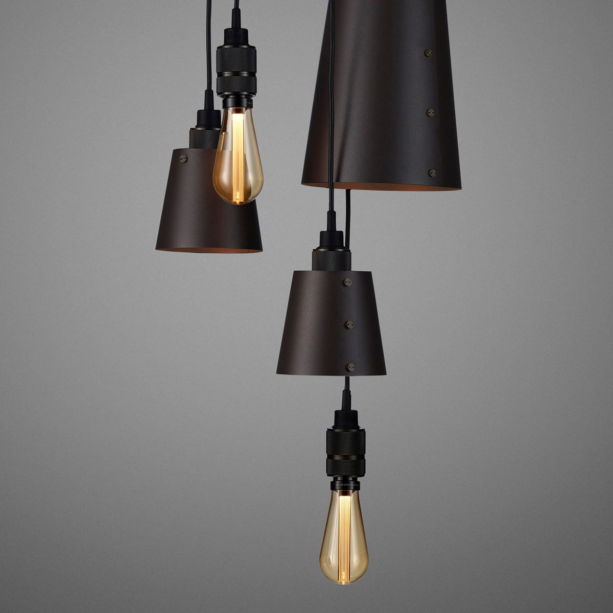 Close-up of the dark metallic pendant lamps and bare bulbs, highlighting their texture.