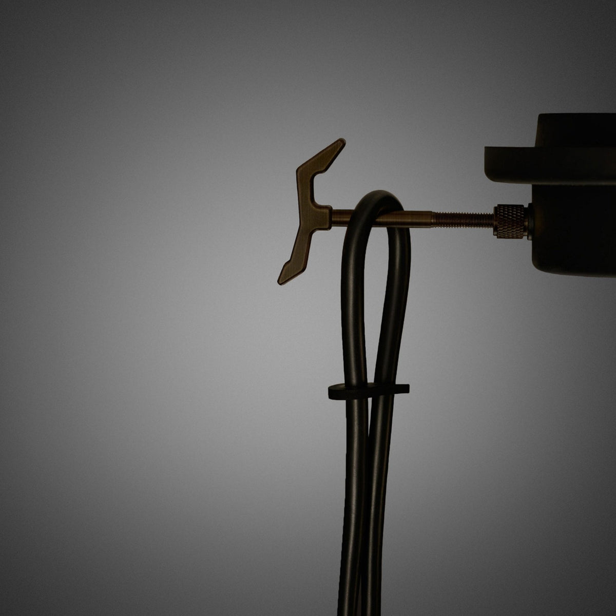 Close-up of a black cable tied with a zip tie, connected to a metal adjustment knob.