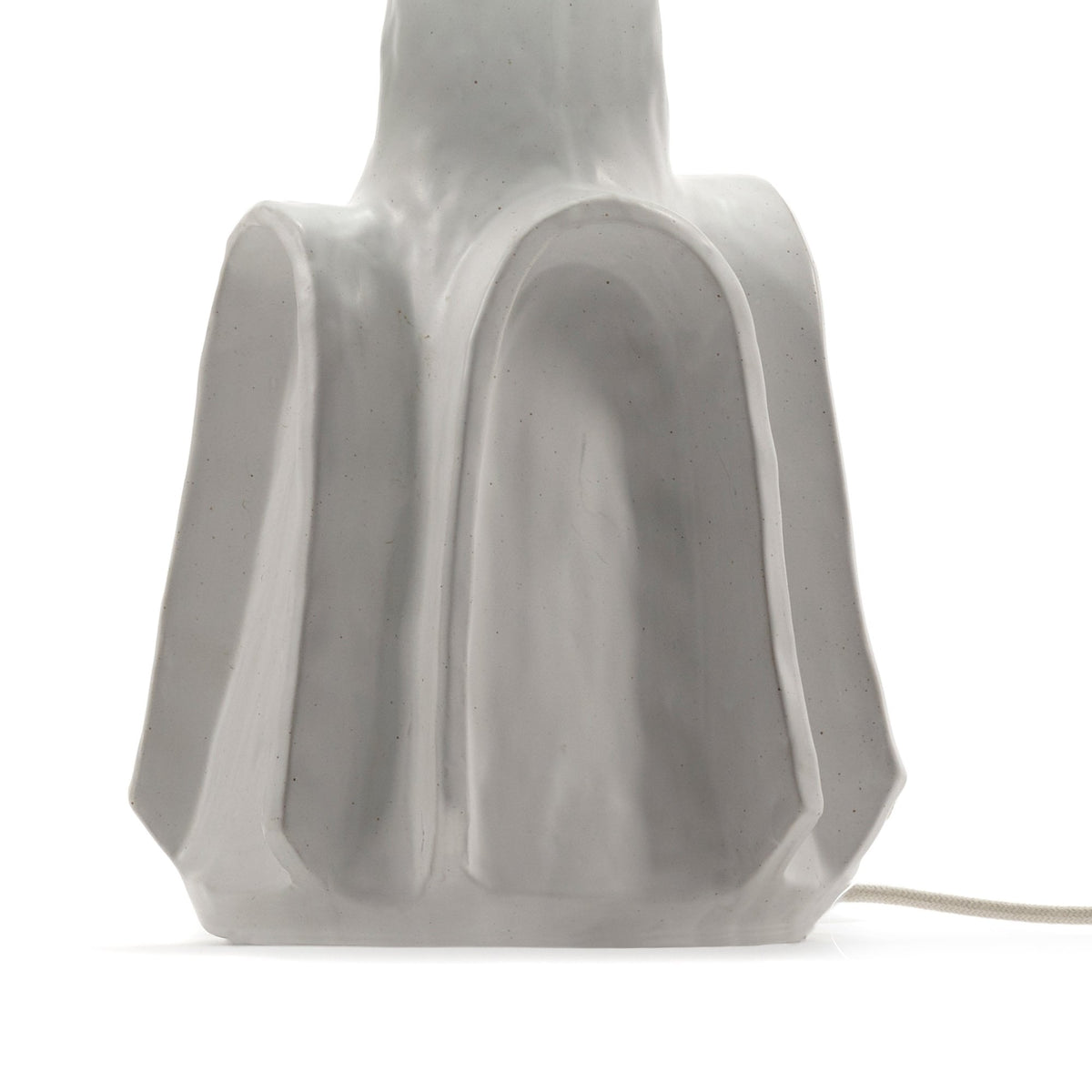 Close-up of the white textured base of a modern table lamp, featuring sculptural curves.