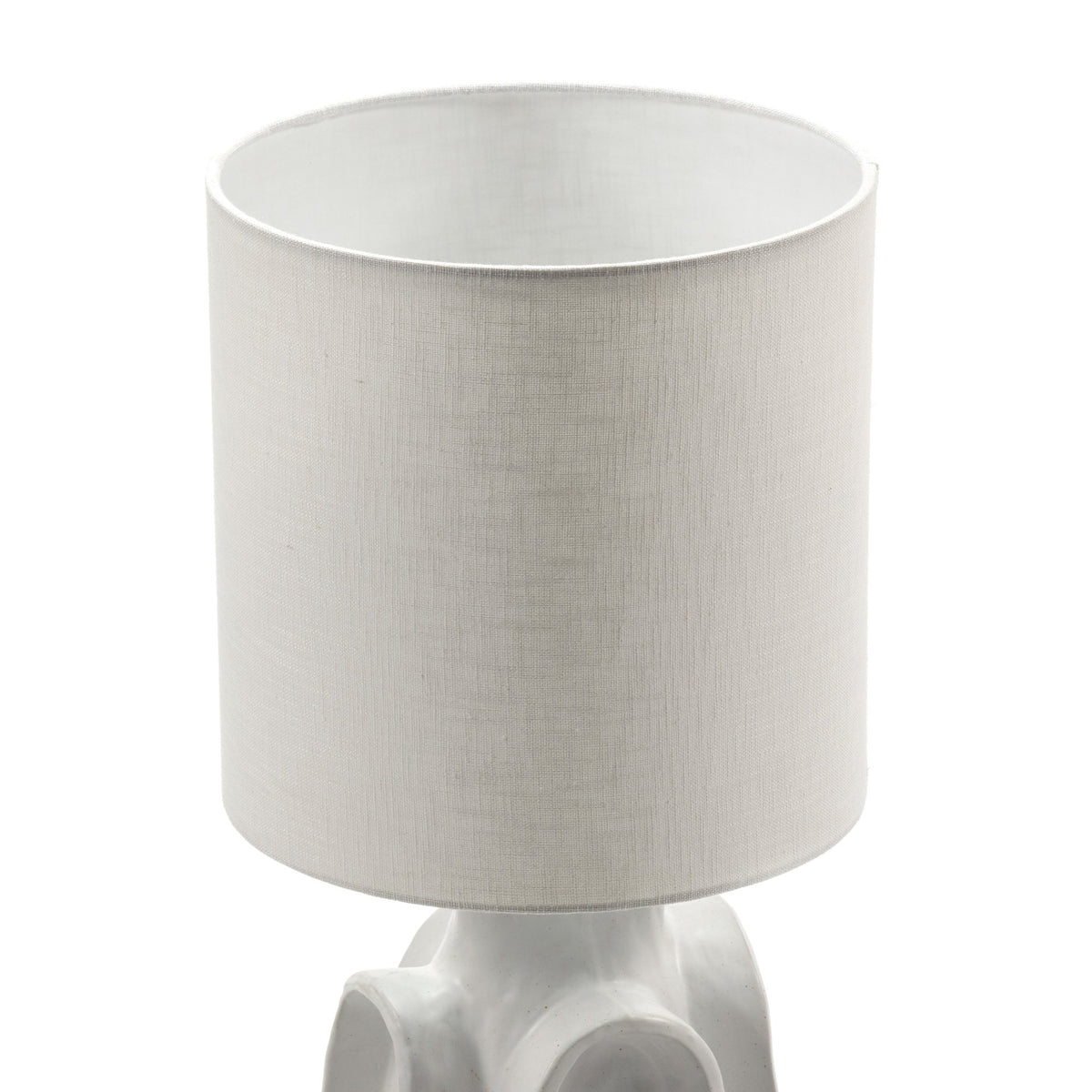Close-up of the light-coloured, cylindrical fabric shade on a modern table lamp.
