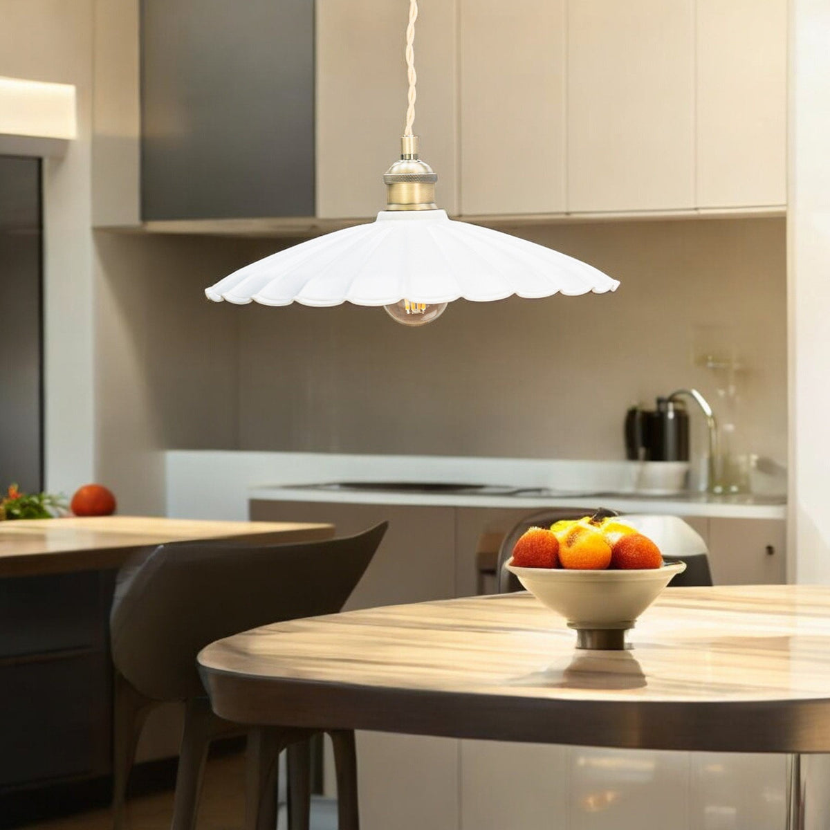 White scalloped pendant light with an exposed bulb hanging over a wooden kitchen island with a fruit bowl.