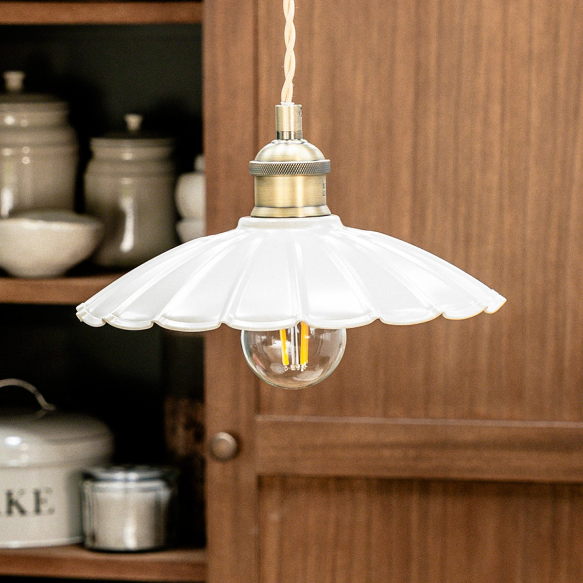 A white fluted glass pendant light with a brass fitting and an exposed filament bulb.