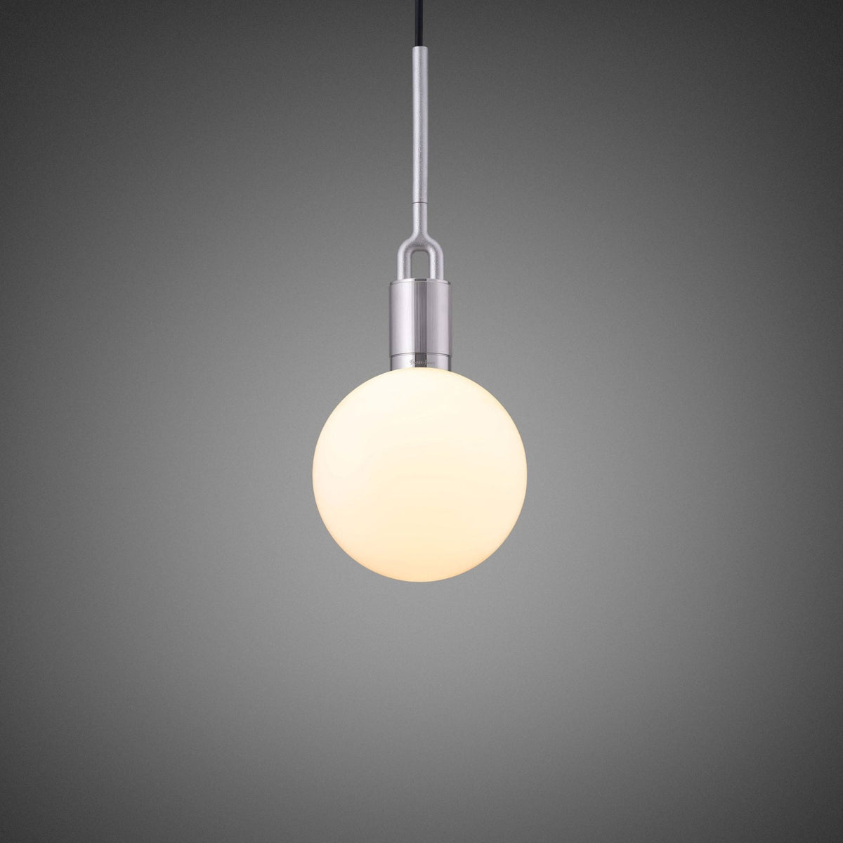 A single, spherical, glowing light bulb hangs from a brushed metal fixture against a dark grey background.