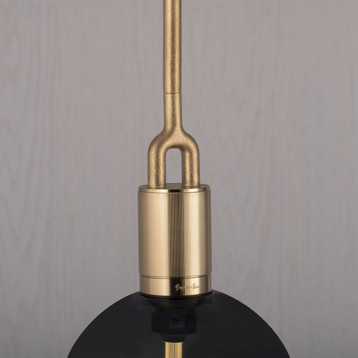 Close-up of a gold pendant light fixture with a black shade, featuring textured metal details.