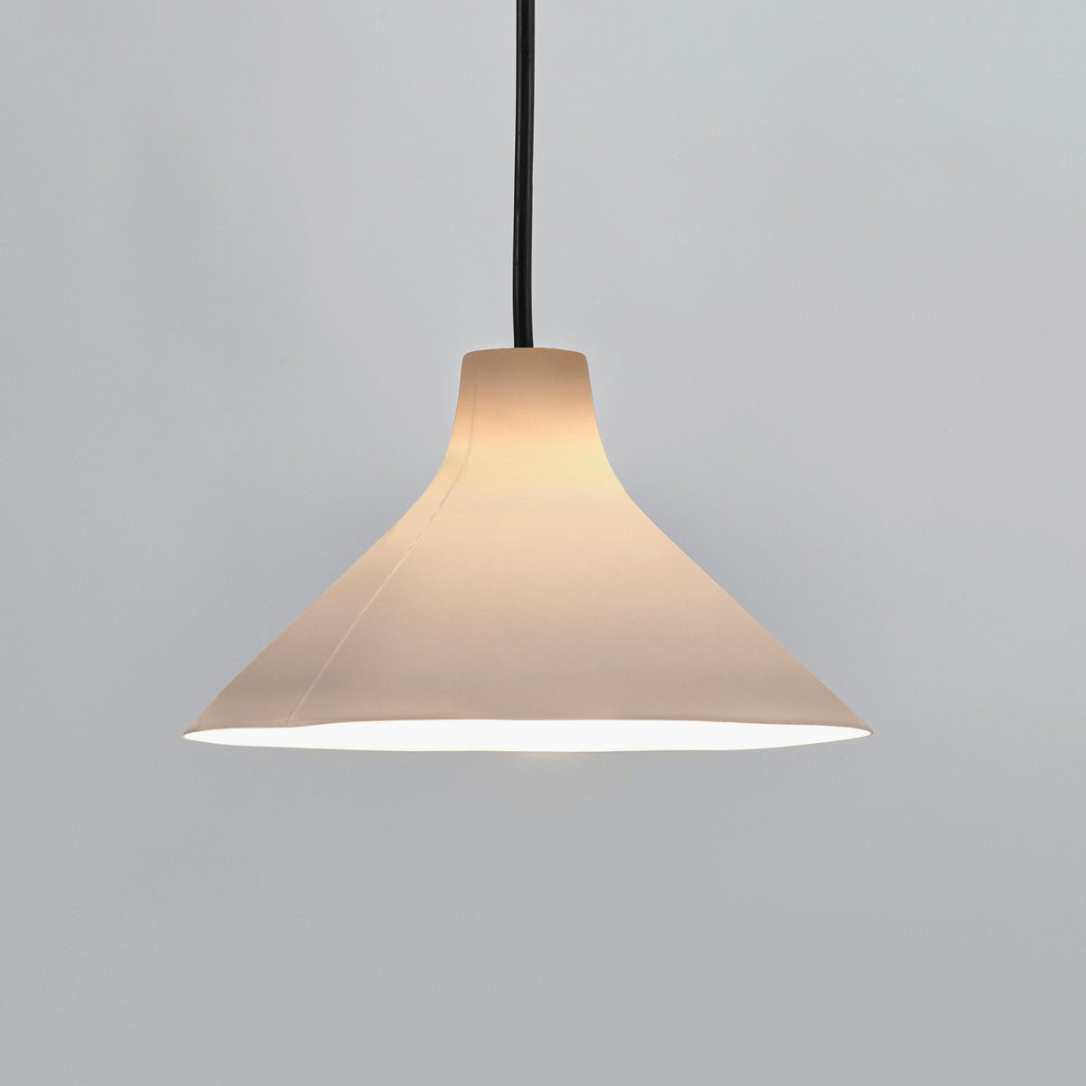 A minimalist white, cone-shaped pendant light with a black cord, providing soft illumination.