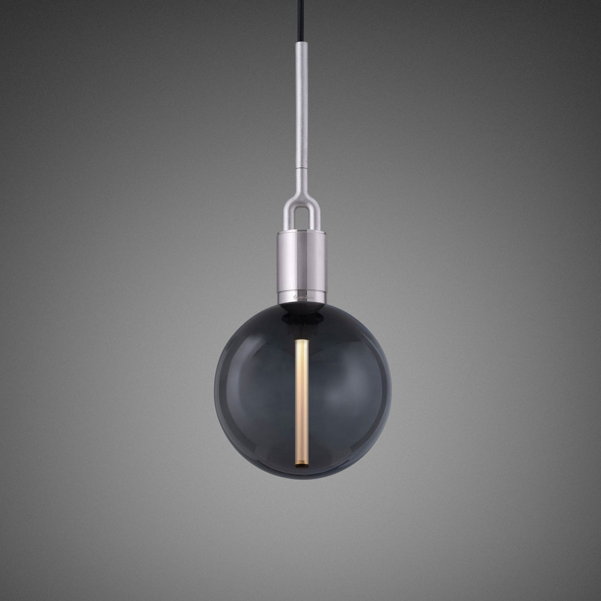 A modern pendant light with a smoked glass globe and a vertical brass filament, suspended from a brushed metal rod.
