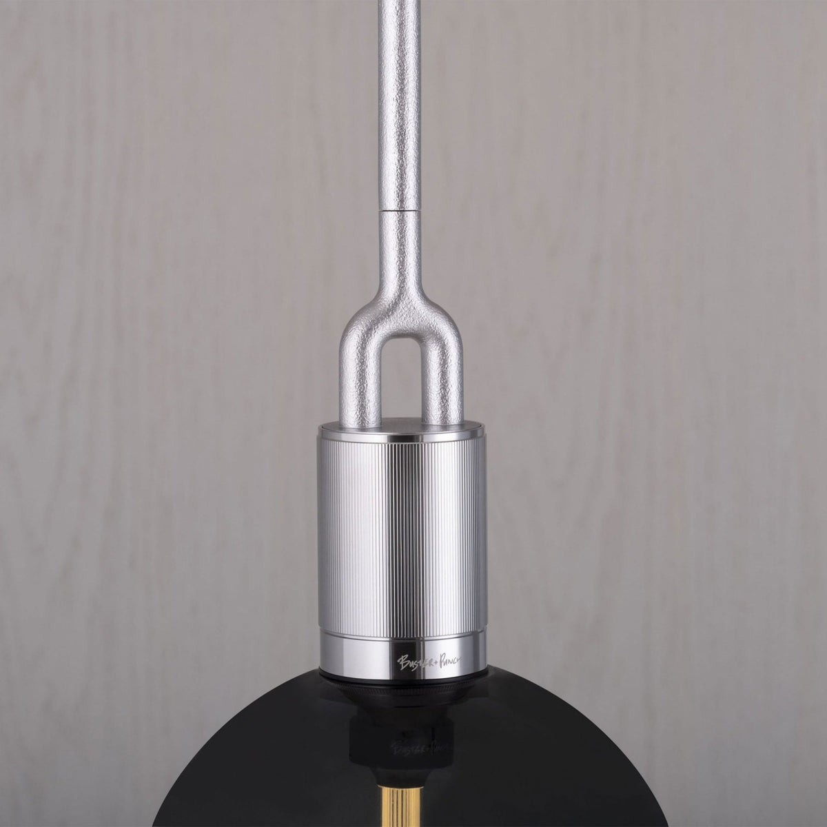 Close-up of a silver pendant light fixture with a black shade, featuring textured and ribbed details.