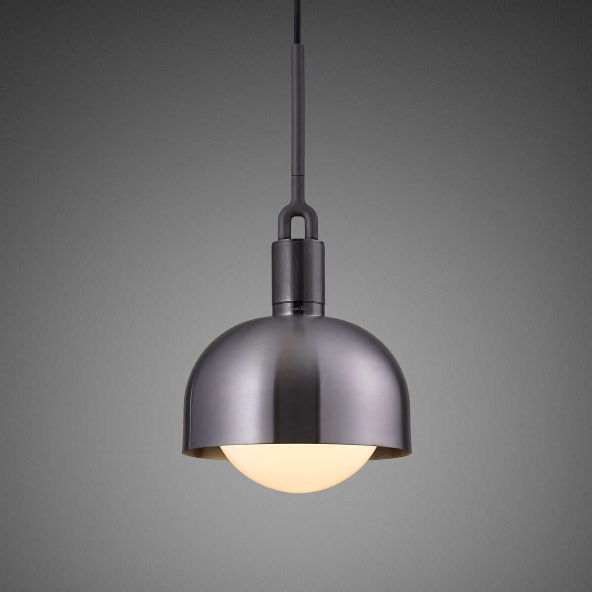 A modern pendant light with a brushed metal dome shade and a glowing spherical bulb.