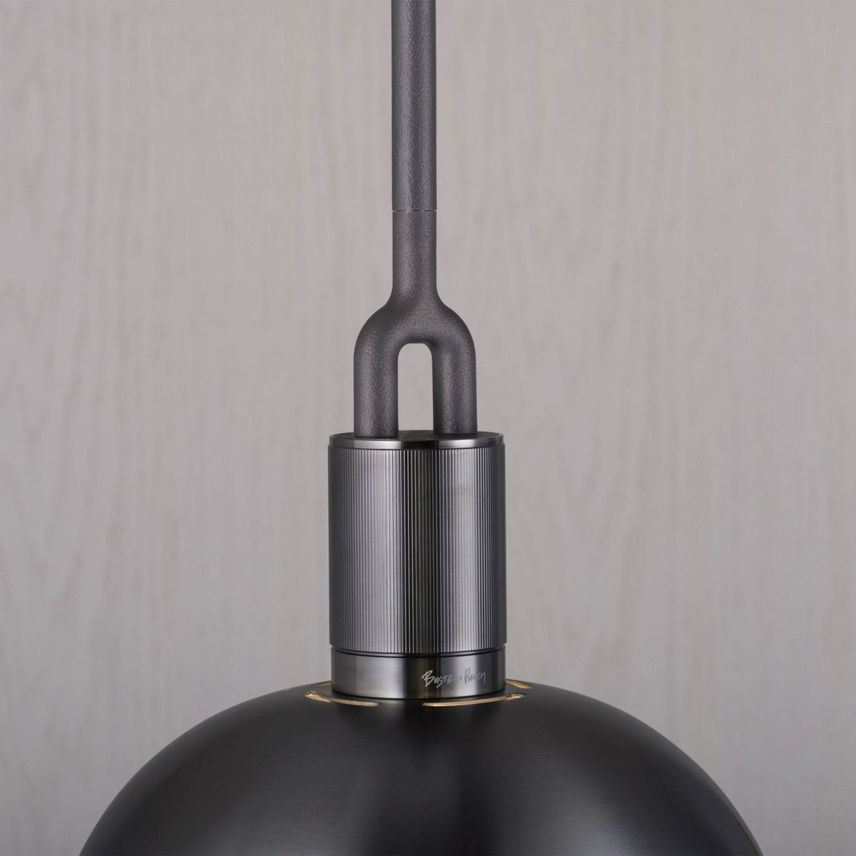 Close-up of a dark grey pendant light with a textured rod and a smooth, domed shade. 