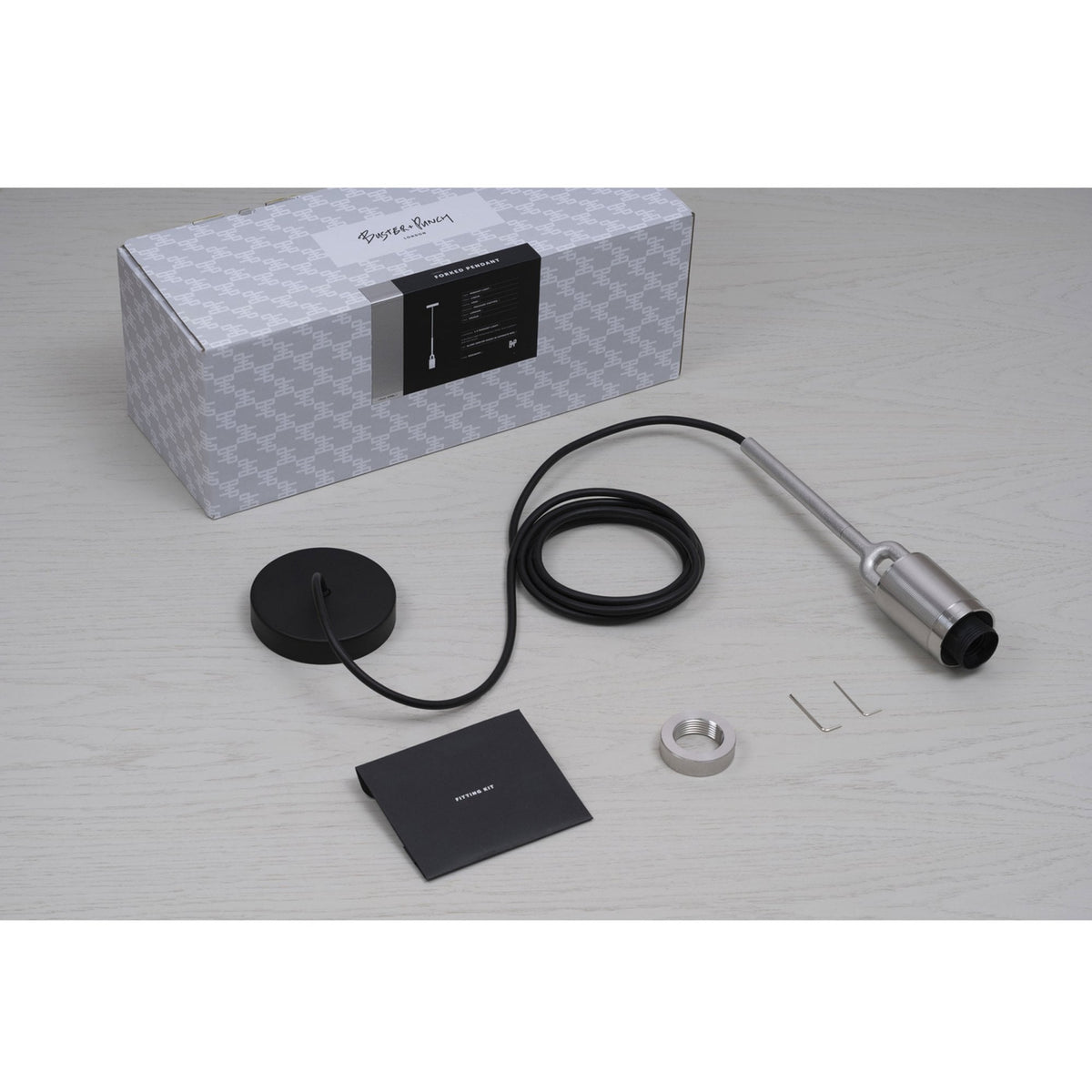 Pendant light kit with black cord, silver fixture, and a gray box with Buster + Punch branding.
