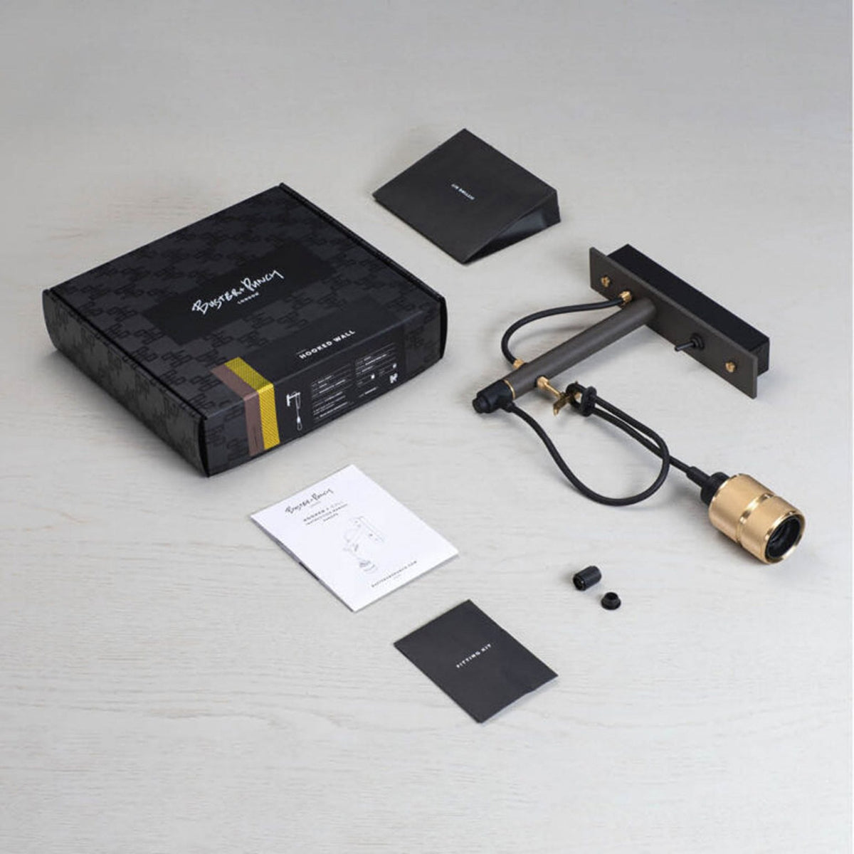 Buster + Punch Hooked Wall light kit with black box, instructions, and brass light fixture.