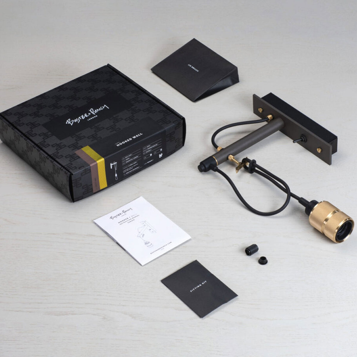 Buster + Punch Hooked Wall light fixture, packaging, and instructions on a white wooden surface.