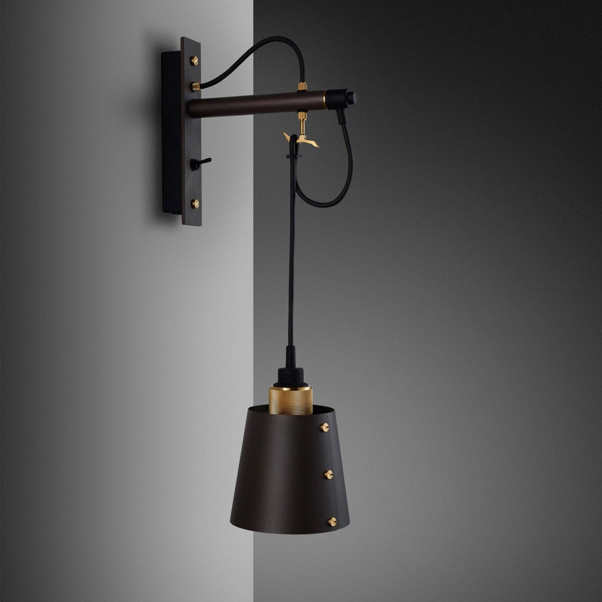 Modern wall sconce with a dark bronze arm and a conical black shade, accented with brass details.
