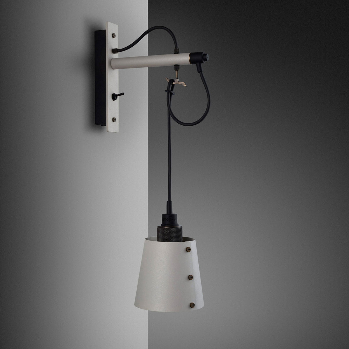 White wall lamp with a black cord and a conical shade, mounted on a light grey wall.