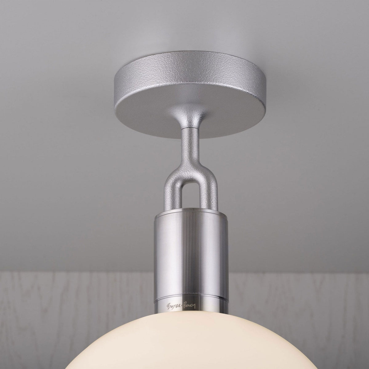 Close-up of a silver ceiling light fixture with a textured finish and a frosted glass dome.