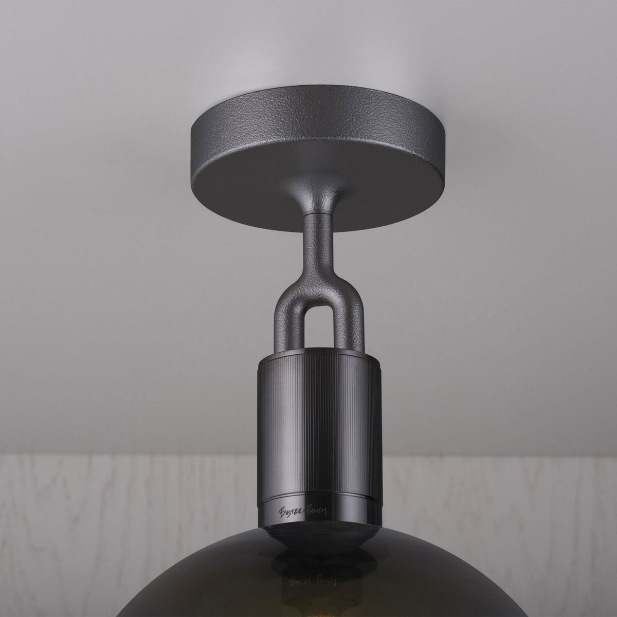 Close-up of a dark grey ceiling light fixture with a textured finish and a ribbed cylindrical base.
