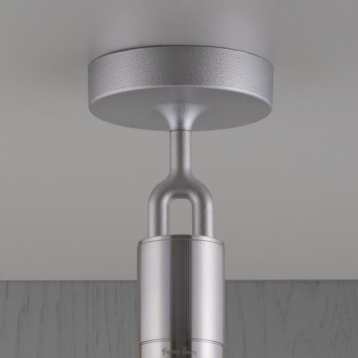 Close-up of a silver ceiling light fixture with a textured base and ribbed cylindrical body. 