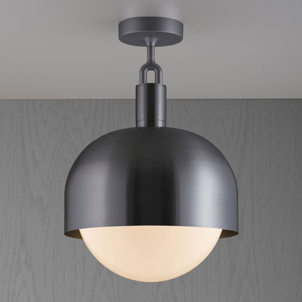 A dark grey semi-flush mount ceiling light with a dome-shaped shade and a glowing white globe diffuser.