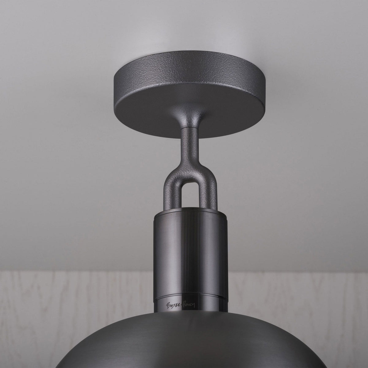 A detailed view of the black metal ceiling mount and suspension of the light fixture.