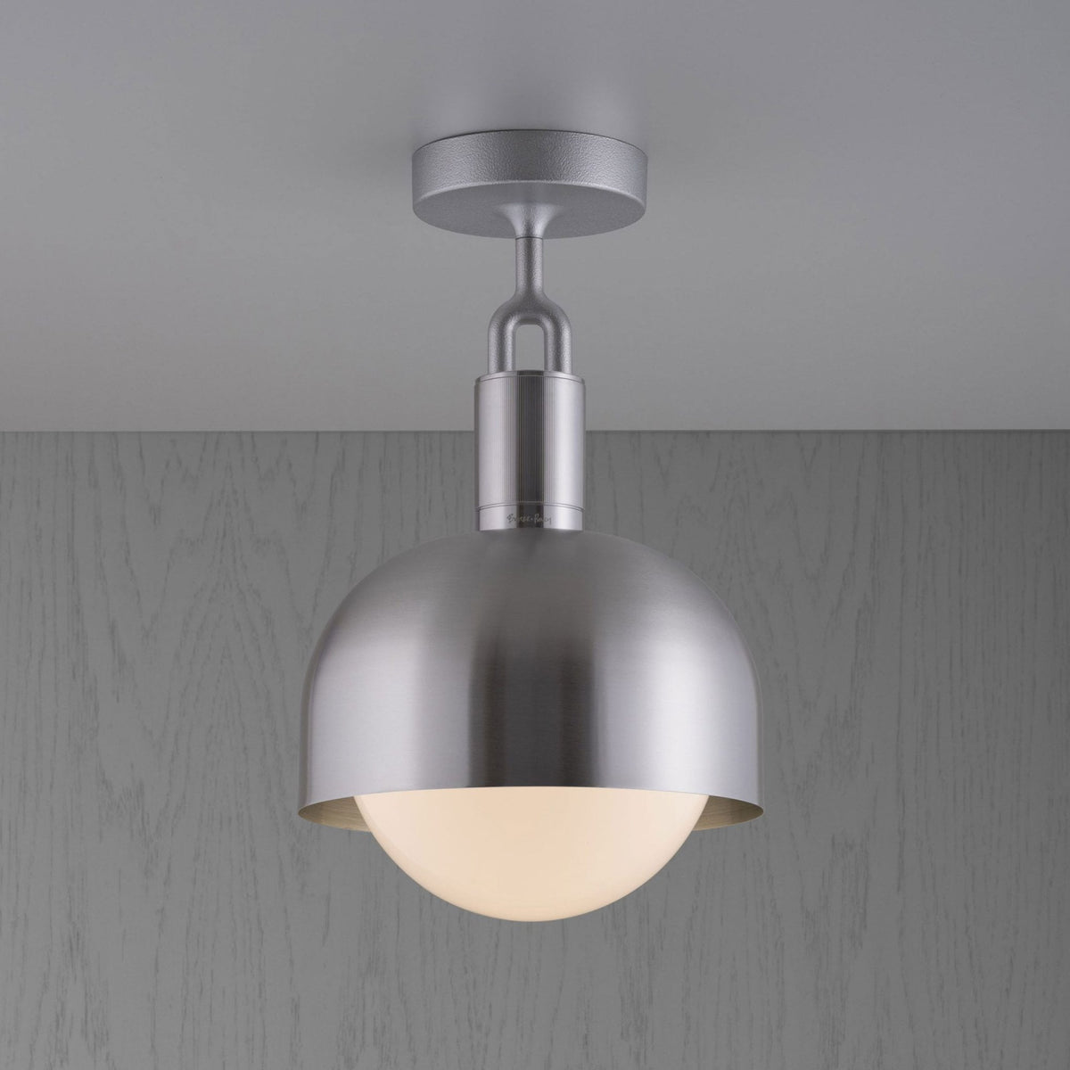 Modern silver ceiling light with a dome shade and a glowing white globe bulb.