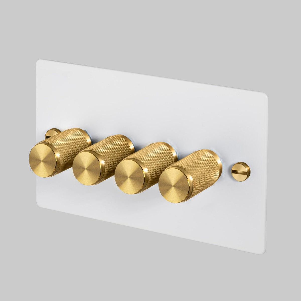 A white dimmer switch faceplate with four solid brass dimmer knobs.