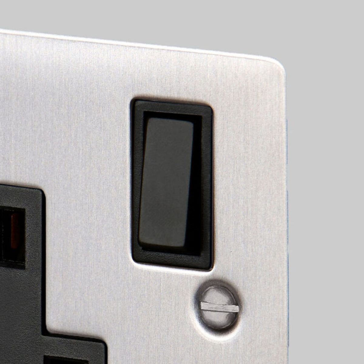 A close-up of the black rocker switch on a brushed steel single socket.