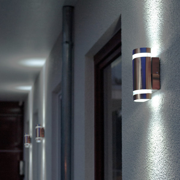 A row of modern outdoor lights illuminating a white wall at night.