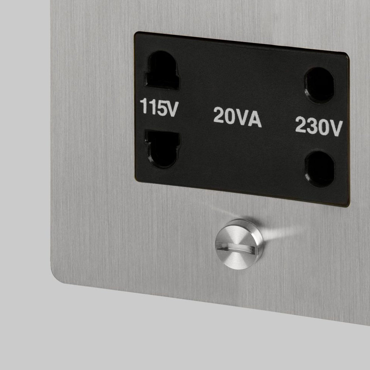 Close-up of a brushed metal panel with a black power outlet, labeled 115V, 20VA, and 230V.