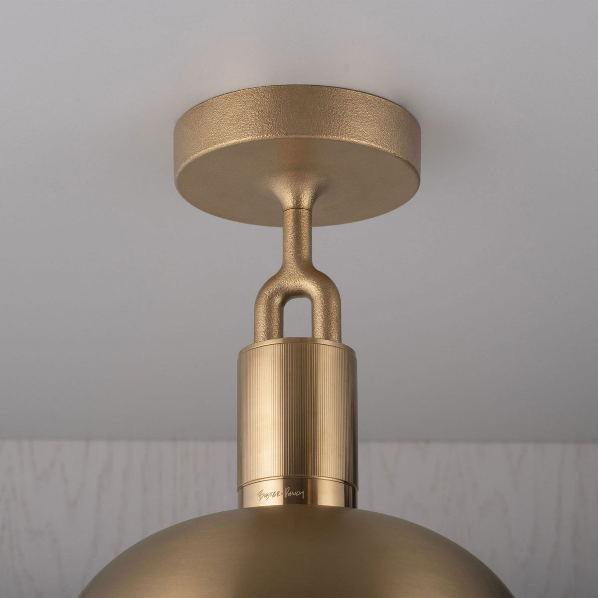 Close-up of a gold ceiling light fixture with a textured base and a smooth, curved shade.