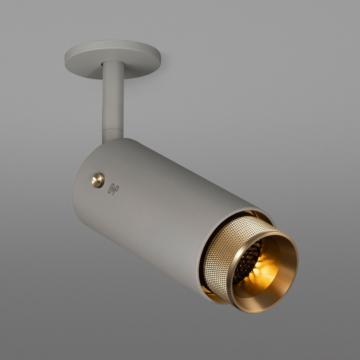 Modern grey ceiling spotlight with a gold inner casing and warm light, angled downwards.