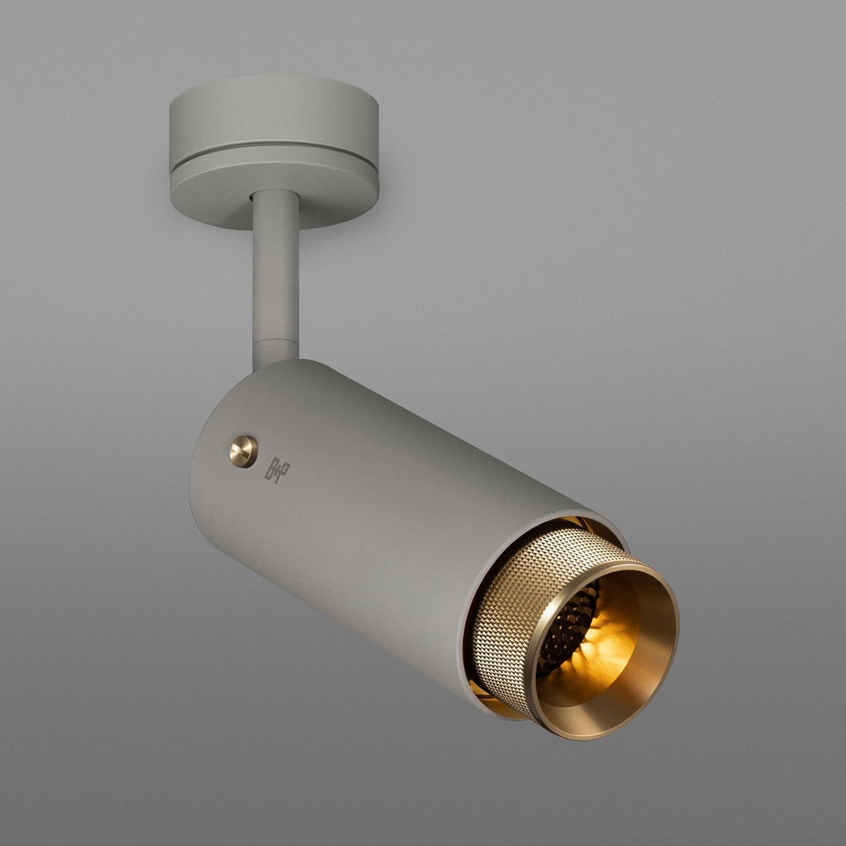 A modern grey ceiling spotlight with a brass-colored inner reflector and a warm glow.