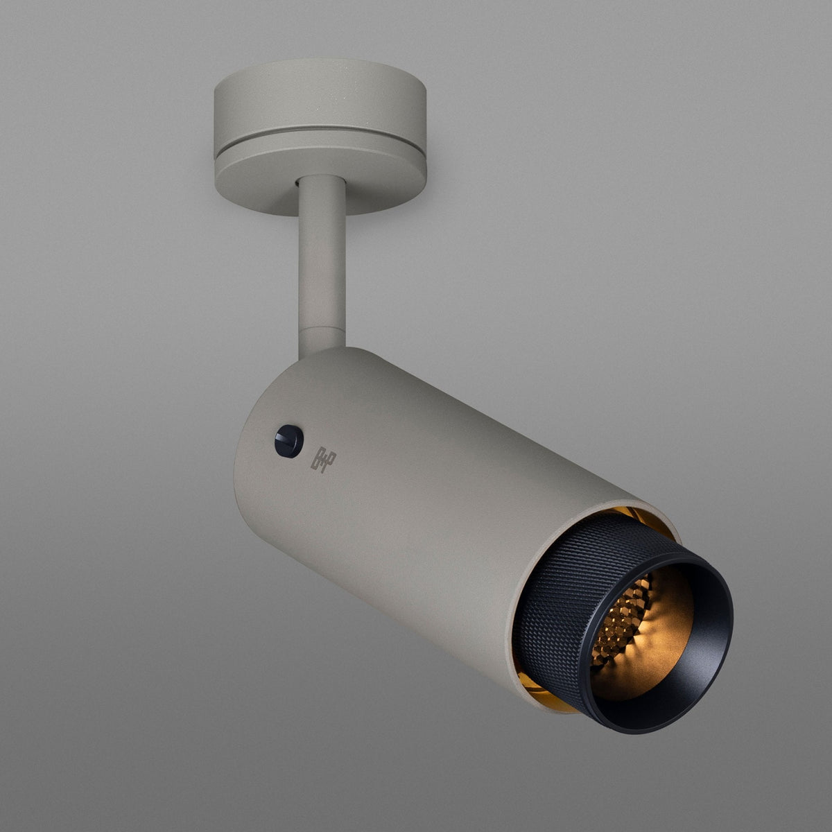 Modern beige ceiling spotlight with a black textured inner ring and warm glowing light.