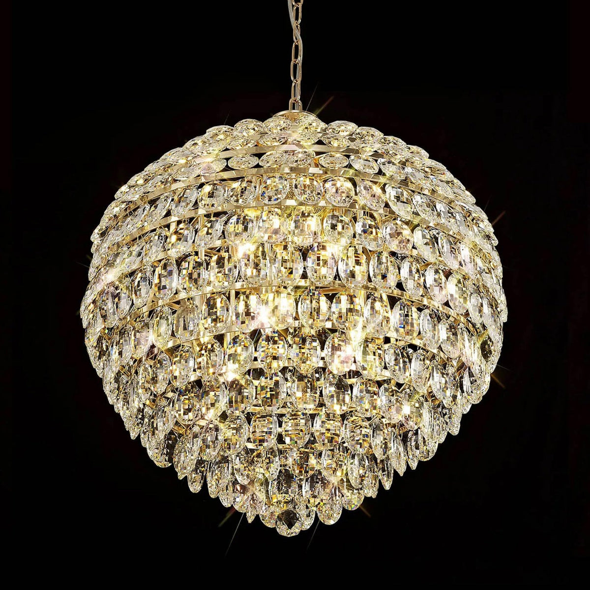 A shimmering, spherical crystal chandelier with internal lights glowing against a dark background.