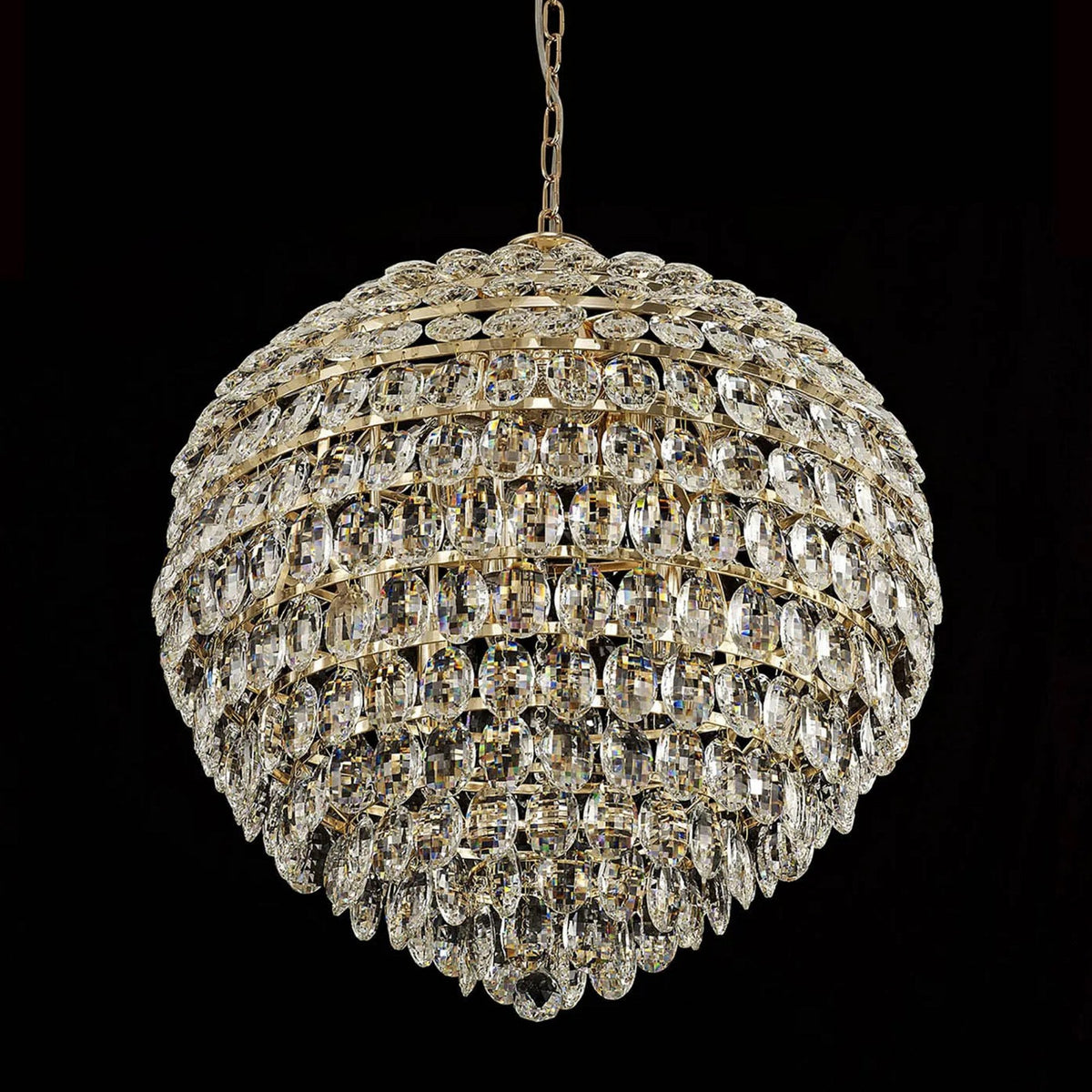 A grand, spherical crystal chandelier with brilliant facets, suspended against a black background.
