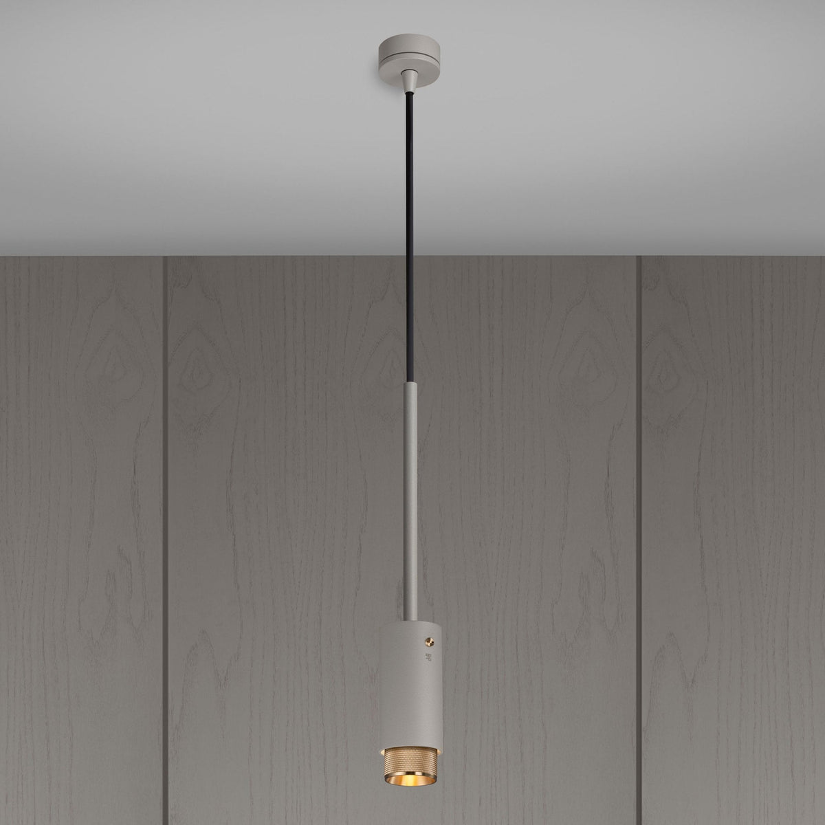 A modern cylindrical pendant light with a grey finish and a brass-colored inner diffuser, hanging from a ceiling.