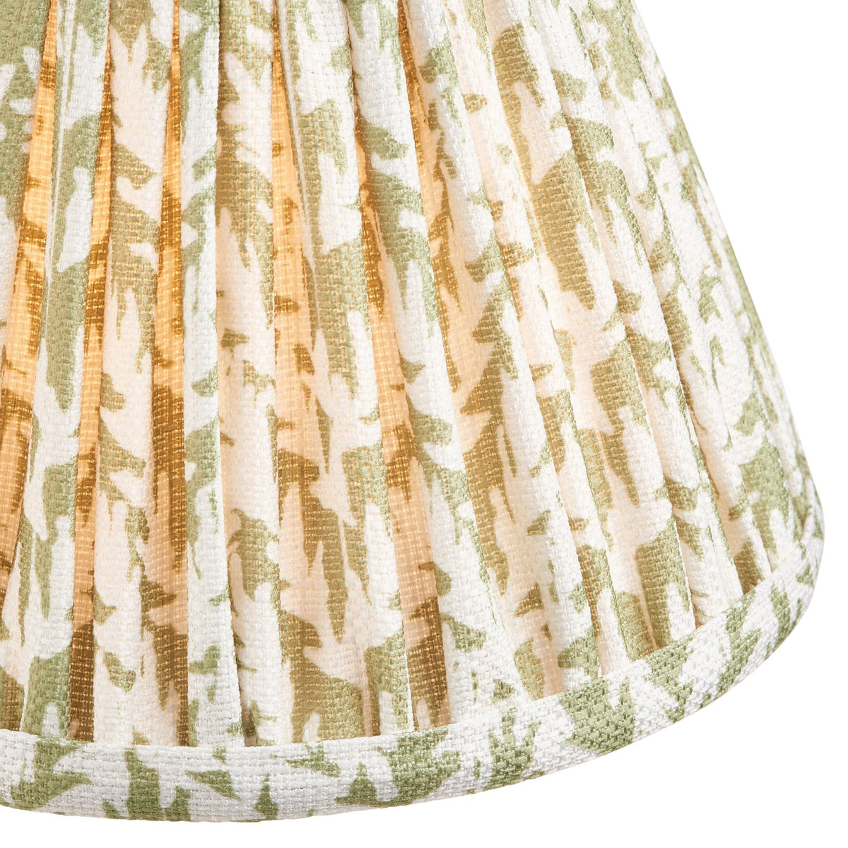 A close-up of a pleated lamp shade with a green and white abstract pattern, lit from within.
