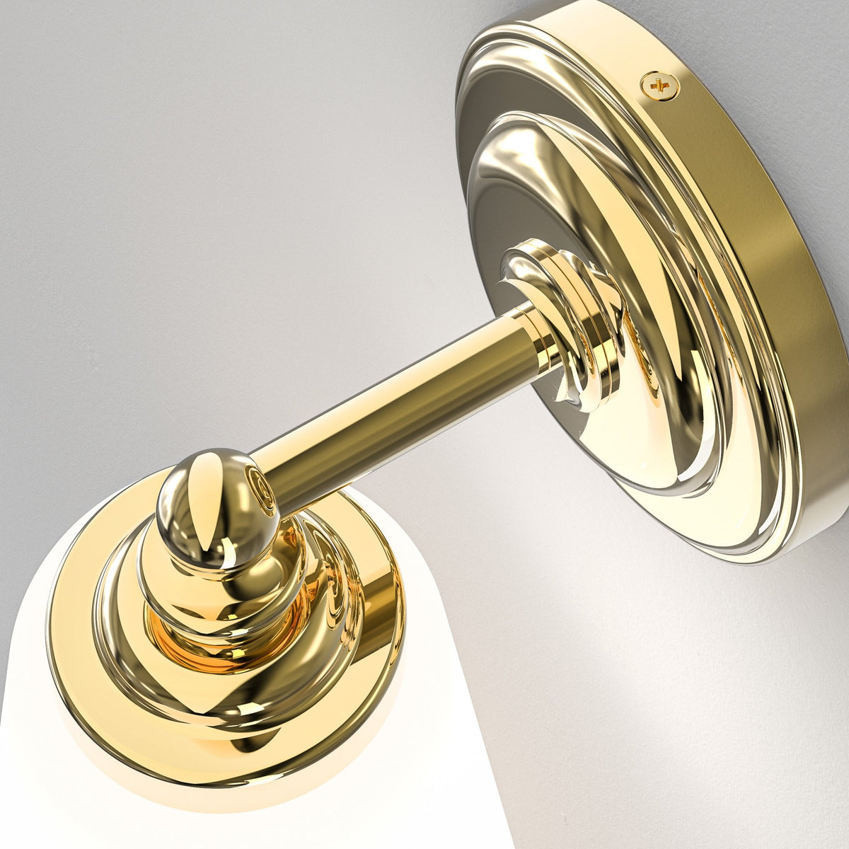 Close-up of the polished brass fitting and arm of a wall light.