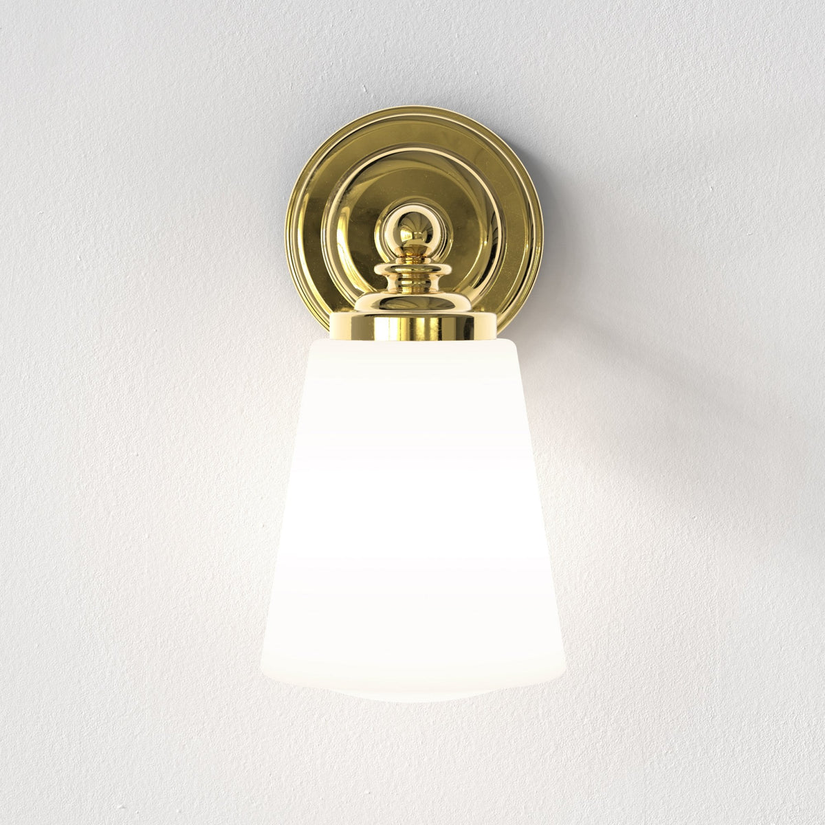 Front view of a polished brass wall light with a conical opaque shade.