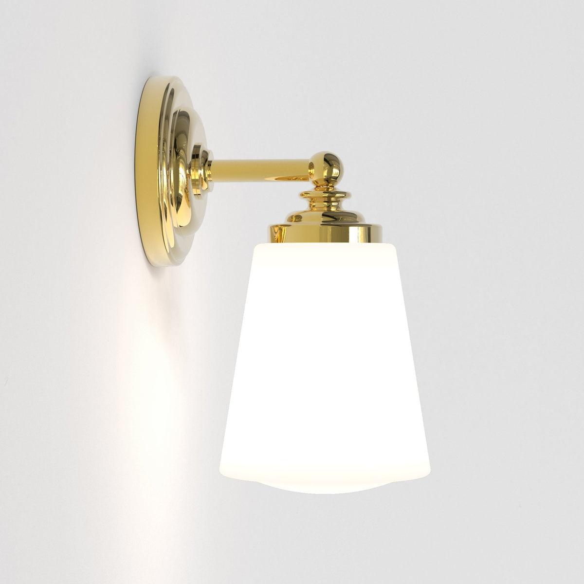Polished brass wall light with a conical opaque shade, seen from an angle.