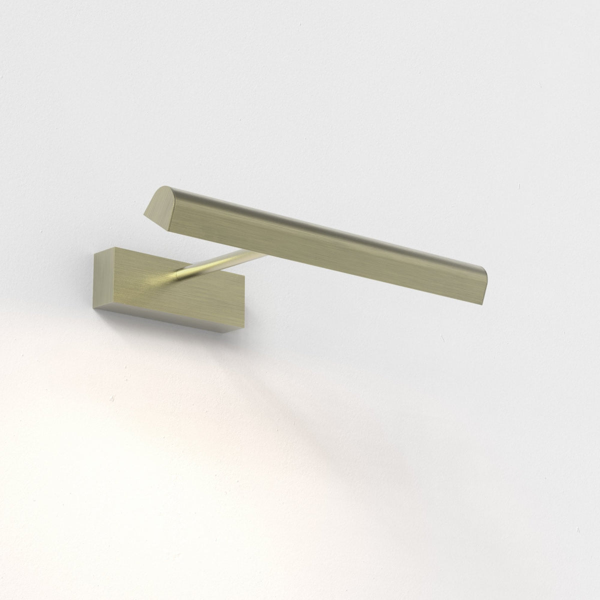 Brushed brass picture light mounted on a white wall, casting a warm glow downwards
