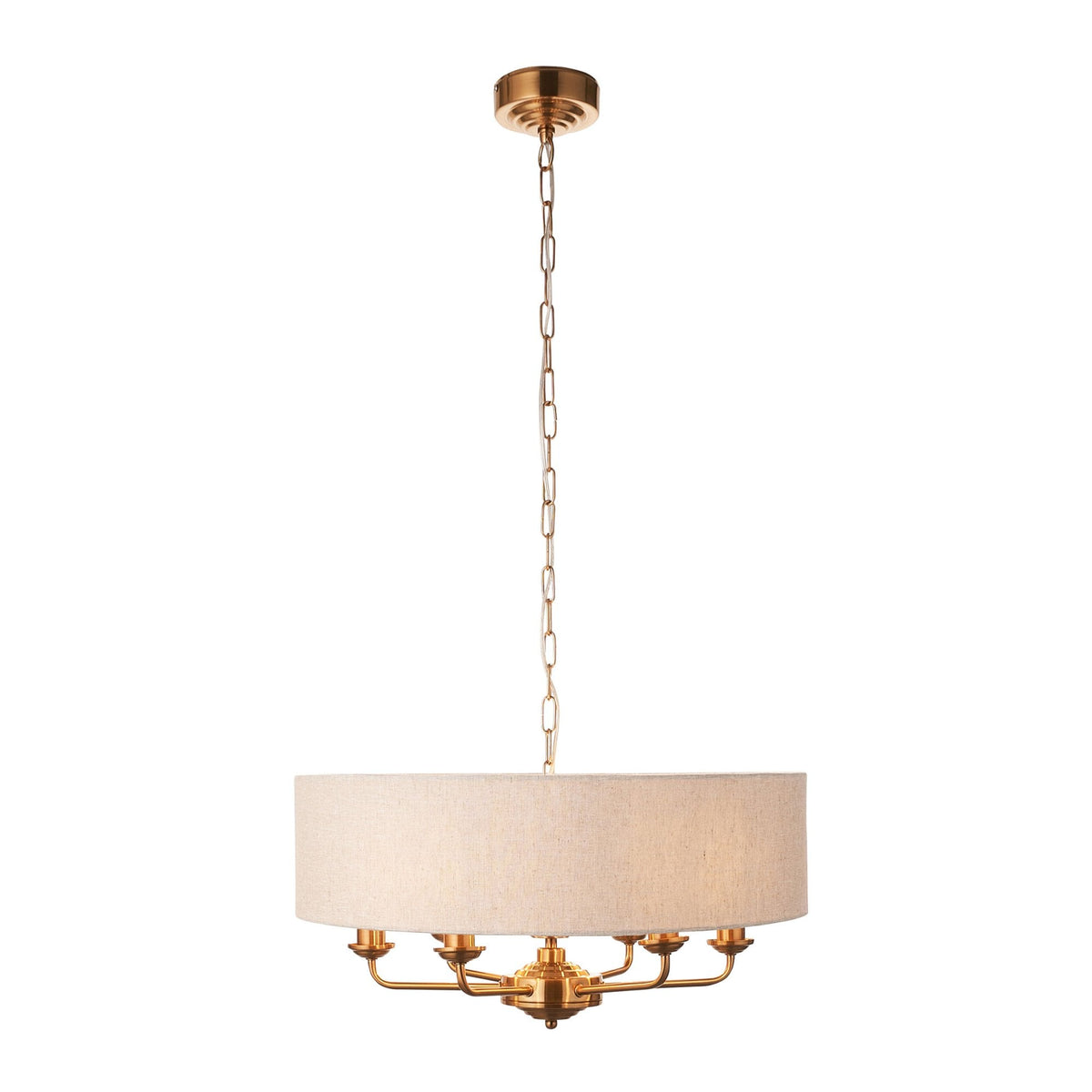 A brass chandelier with a large, round, light-colored fabric shade hangs from a ceiling on a white background.